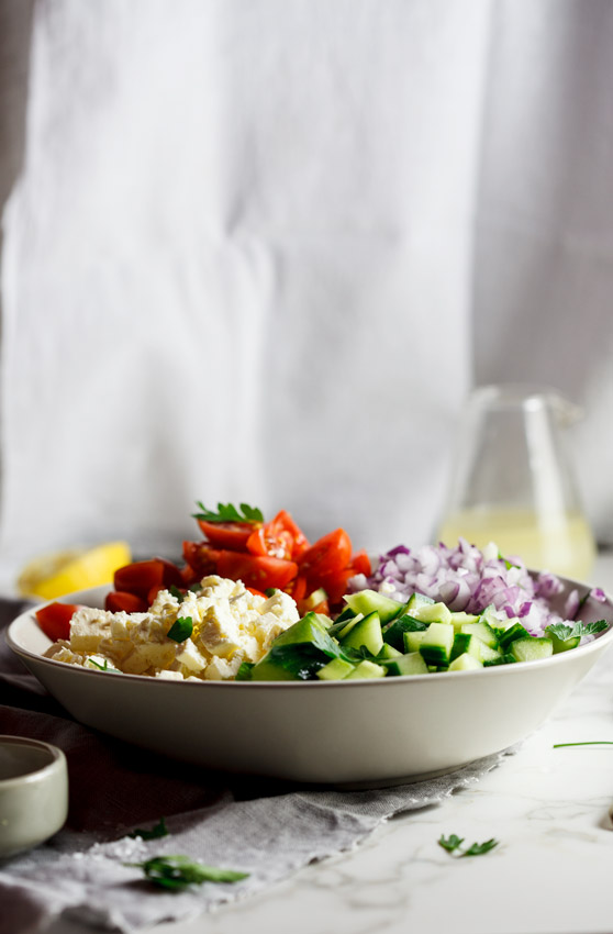 Easy chopped salad with lemon vinaigrette in white bowl on marble table.