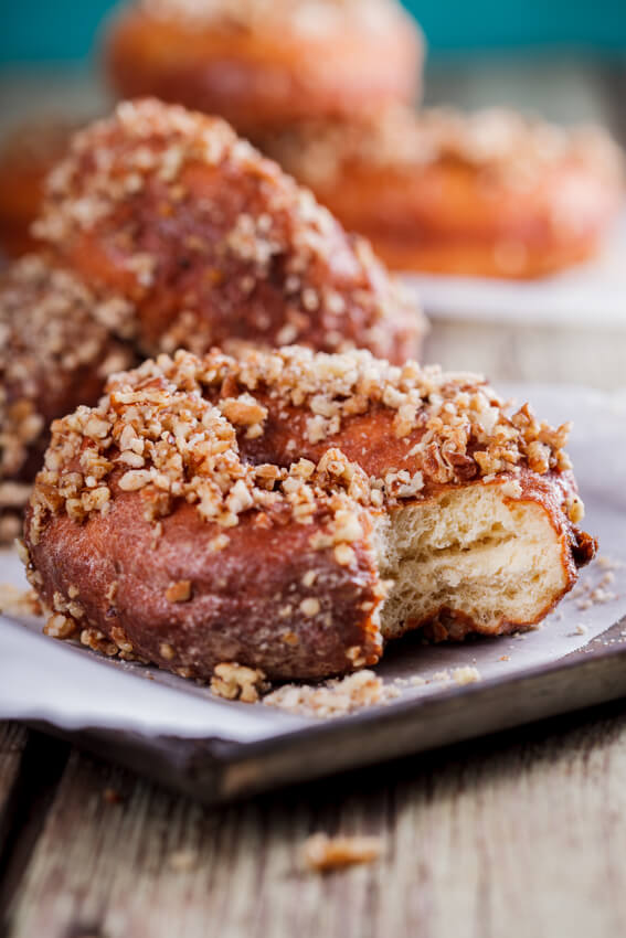 Soft, fluffy yeasted doughnuts covered in caramel glaze and dunked in crunchy cinnamon-flavored nuts.