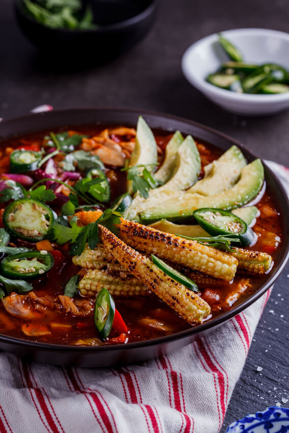 Aromatic Mexican chicken soup with sweet, charred baby corn makes for a showstopping meal when served with fresh jalapeños and avocado.
