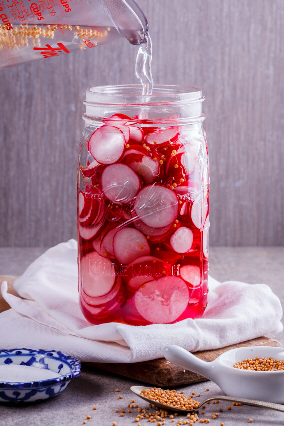 Radishes being pickled in jar. 