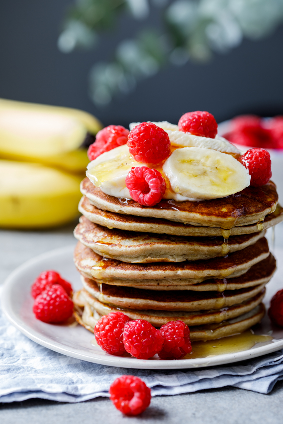 Easy blender banana oat pancakes topped with fresh fruit and honey 