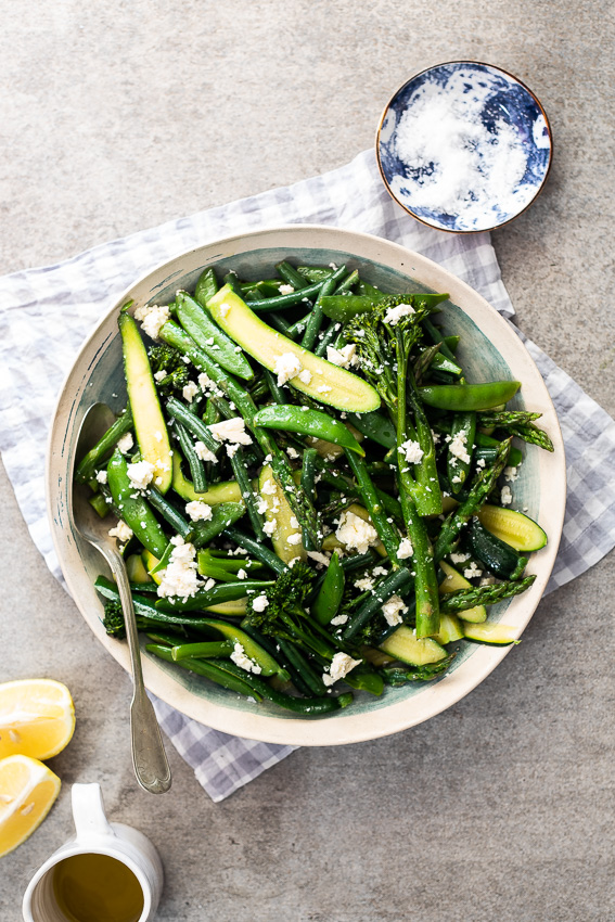 Easy steamed spring vegetables with feta cheese in blue and white bowl