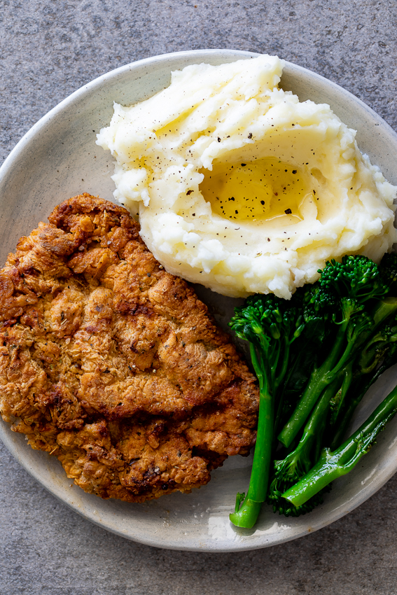 Crispy chicken fried steak with mashed potatoes and broccoli.