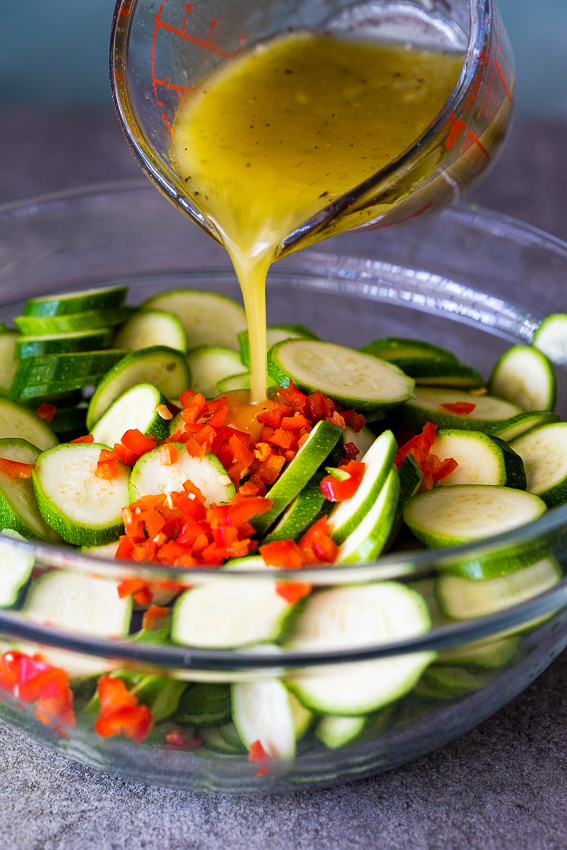 Lemon olive oil marinade poured onto zucchini salad 