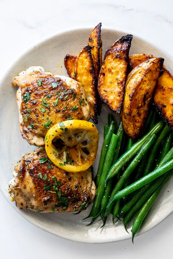 Lemon pepper chicken thighs with potato wedges and green beans.