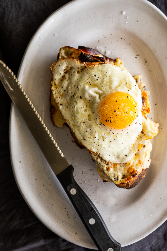 Croque madame on plate with sharp knife.