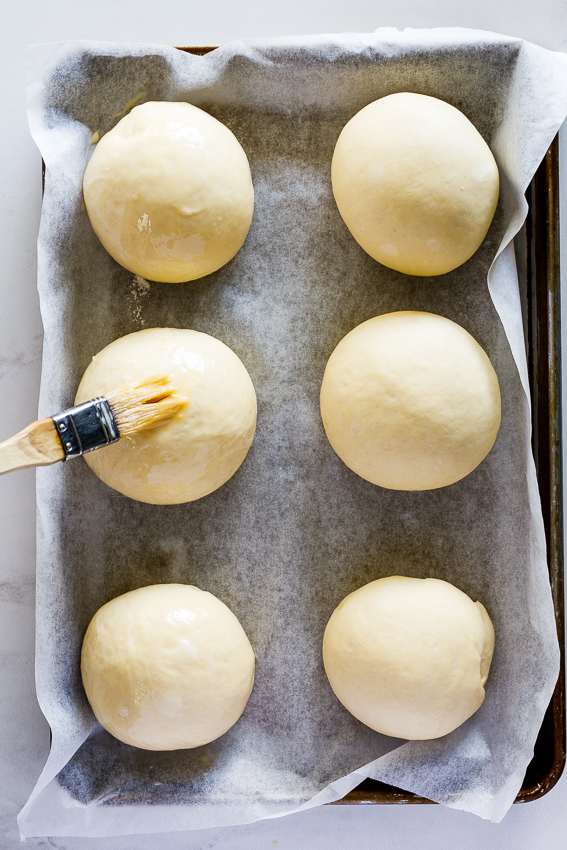 Bread rolls being egg washed.