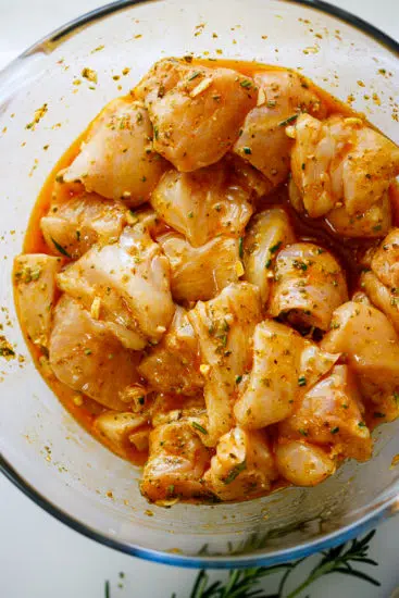 Chicken marinating in olive oil, lemon, herbs and garlic.