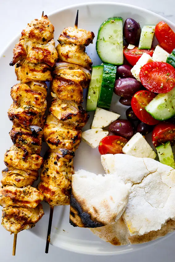 Greek grilled chicken skewers with salad and pita.