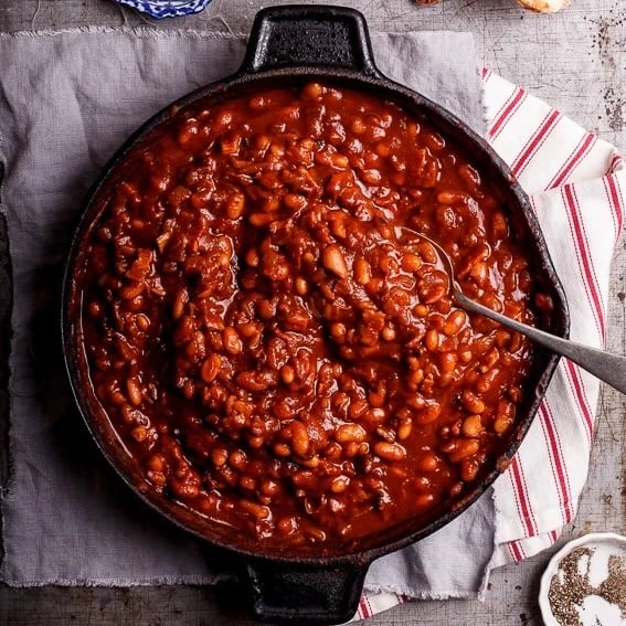 Sweet and smoky cowboy beans in a black skillet.
