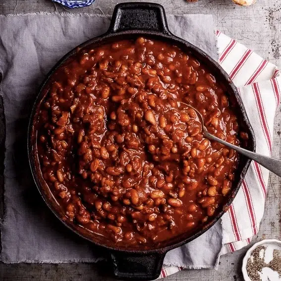Sweet and smoky cowboy beans in a black skillet.
