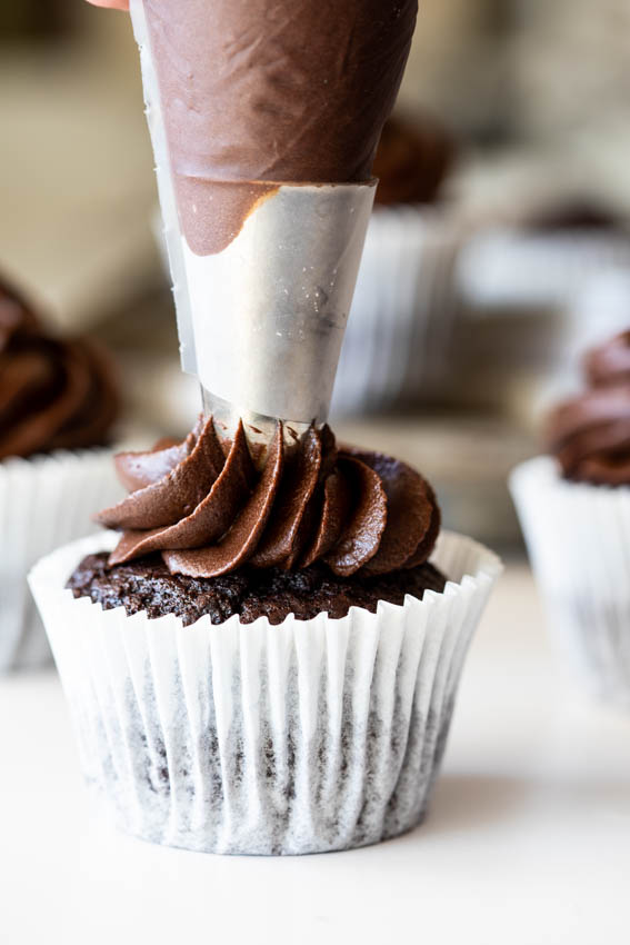 Cupcakes being frosted with buttercream.