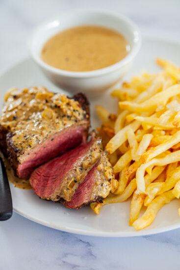 Juicy steak with creamy pepper sauce and fries.