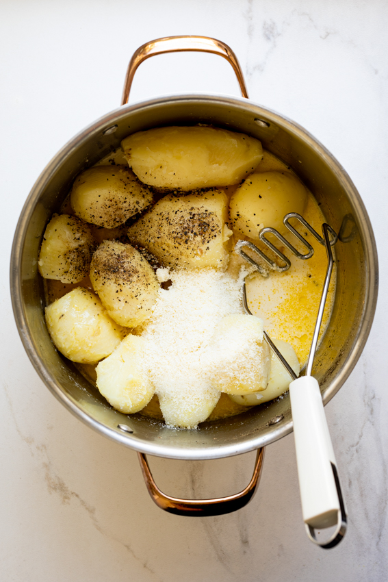 Potatoes in pot with butter, milk and cheese.