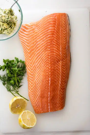 Side of salmon rubbed with garlic herb butter before being baked.
