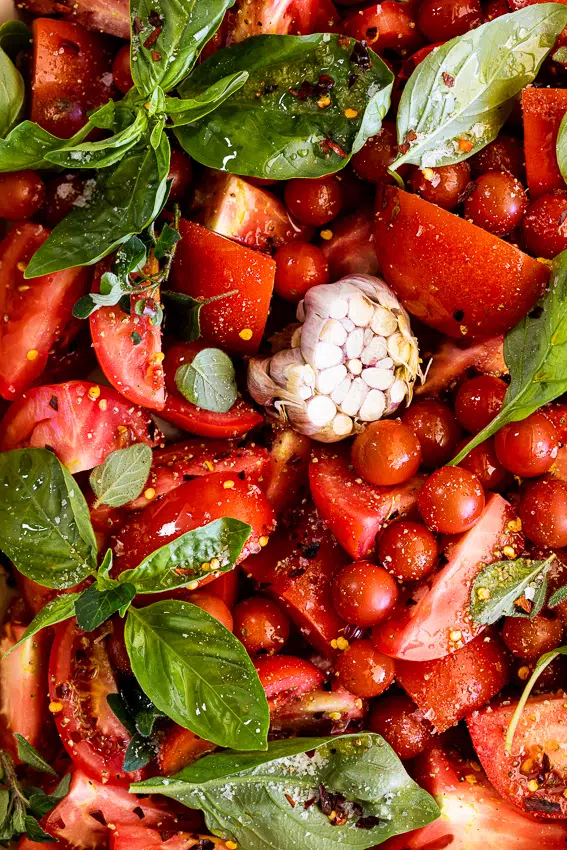 Tomatoes, basil and garlic in baking dish.