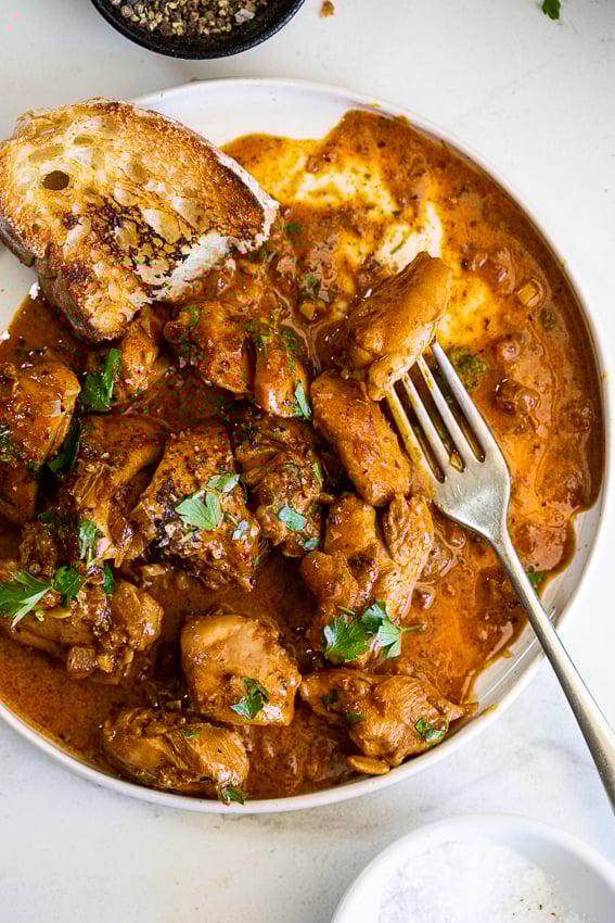 Creamy paprika chicken on serving plate with crusty bread.