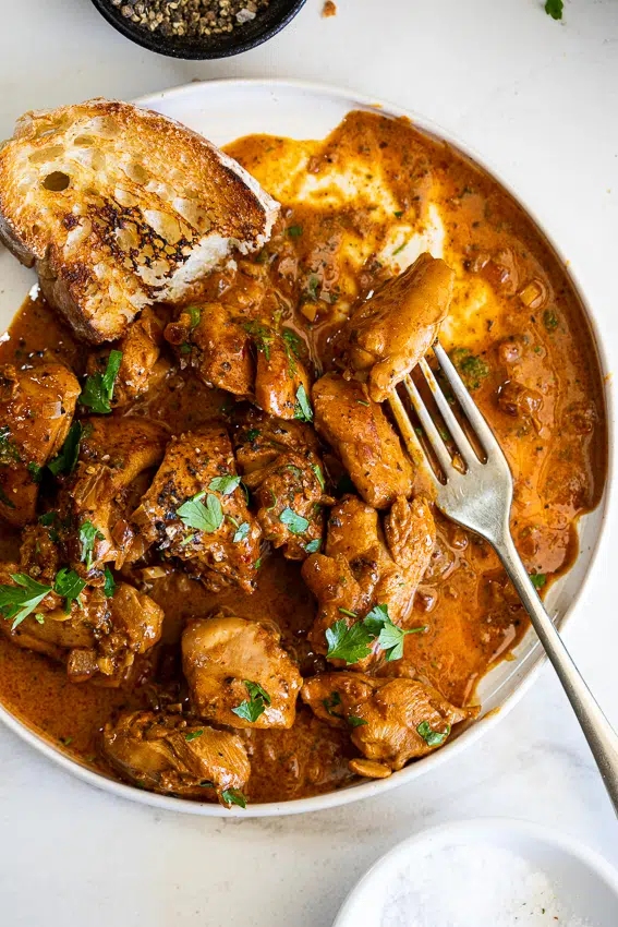 Creamy paprika chicken on serving plate with crusty bread.