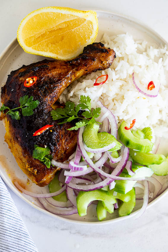 Baked tandoori chicken with rice and cucumber salad.