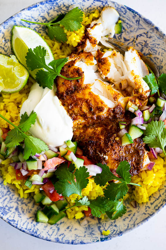 Flaky baked masala flavored fish with turmeric rice and chopped salad