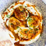 Boiled eggs on a bed of seasoned yogurt with spicy butter.