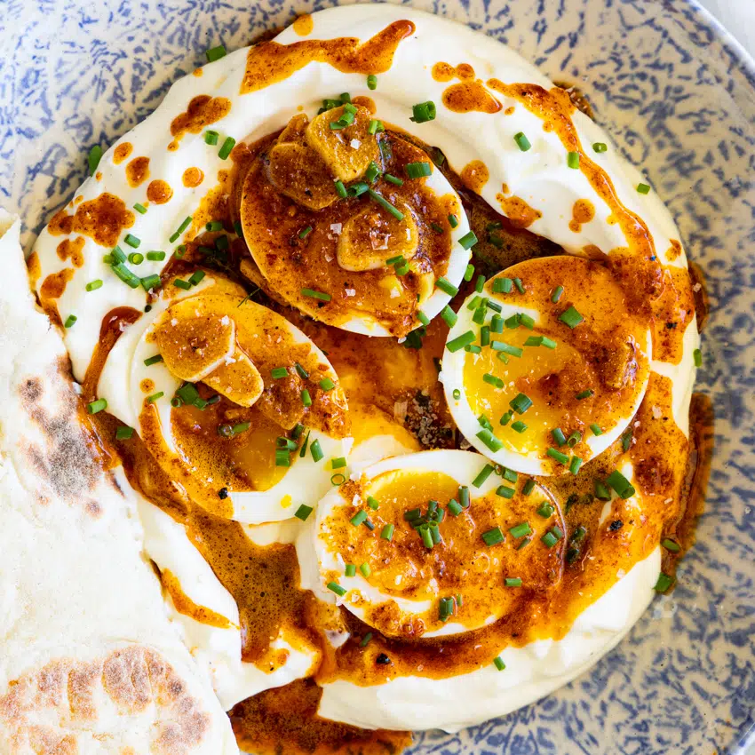 Boiled eggs on a bed of seasoned yogurt with spicy butter.