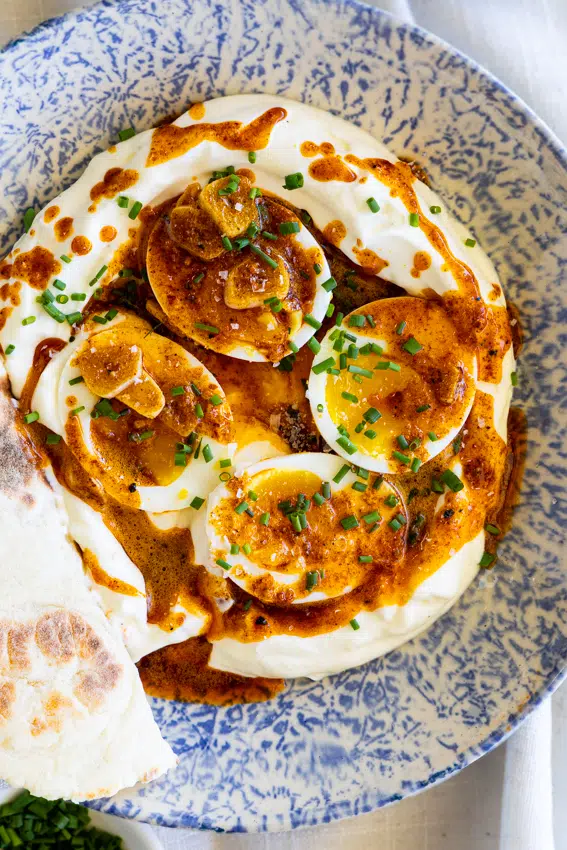 Boiled eggs on a bed of seasoned yogurt with spicy butter.