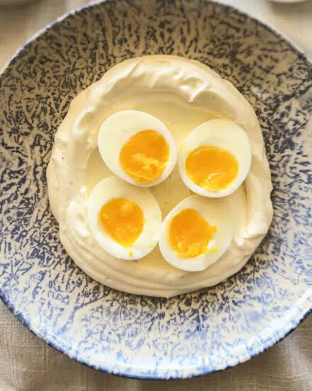 Soft boiled eggs on top of seasoned yogurt.