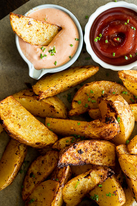 Air fryer potato wedges served with dipping sauces.