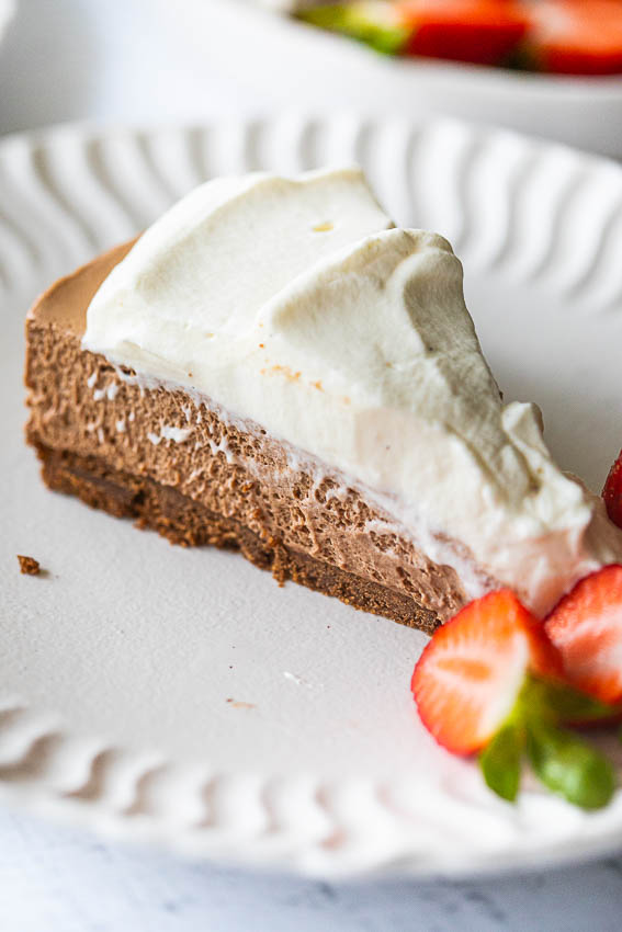 Chocolate mousse pie topped with whipped cream served with fresh strawberries.