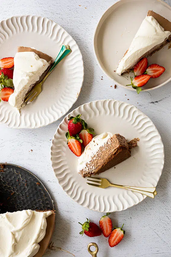 Chocolate mousse pie topped with whipped cream served with fresh strawberries on serving plates.