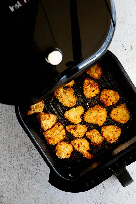 Chicken bites in air fryer basket.