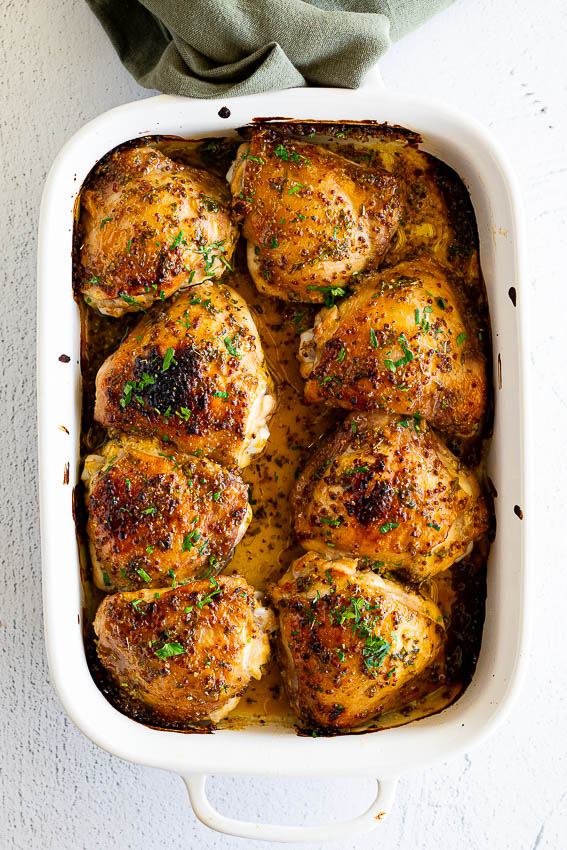Chicken thighs cooked in honey mustard sauce in baking dish.