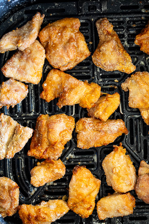 Crispy chicken in air fryer basket.