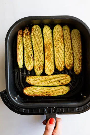 Air fryer zucchini in air fryer basket.