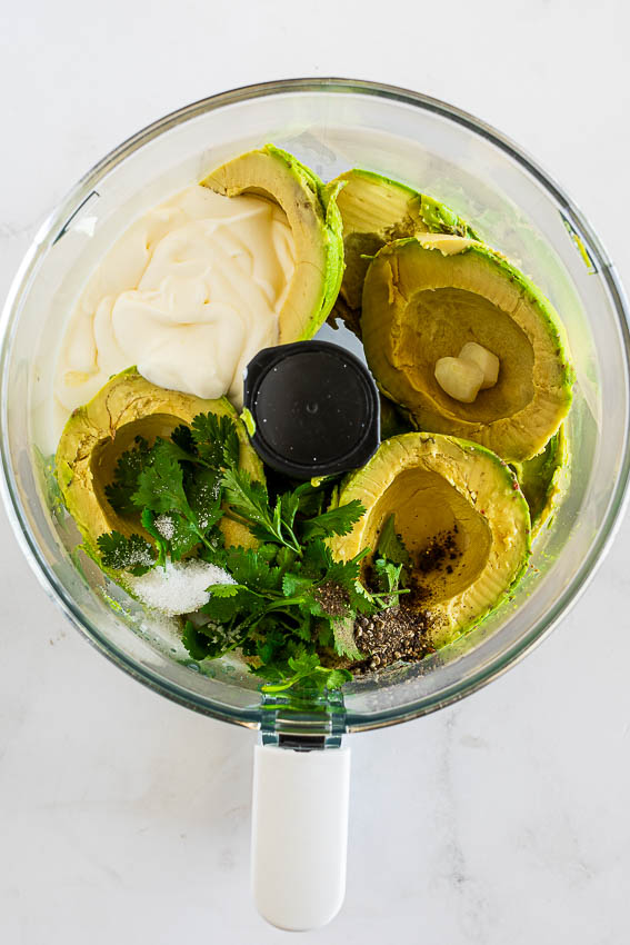 Ingredients for avocado sauce in the bowl of a blender.
