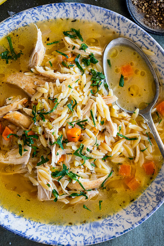Lemon chicken orzo soup in serving bowl with soup spoon.