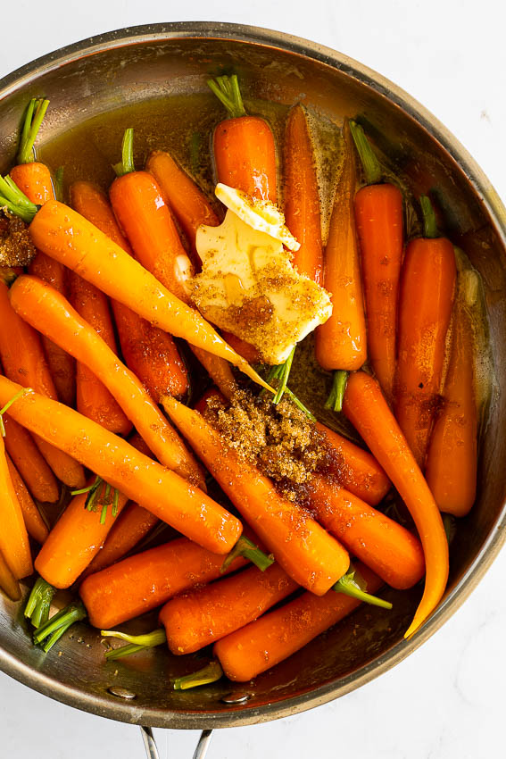 Carrots in pan with butter, sugar, maple syrup and thyme