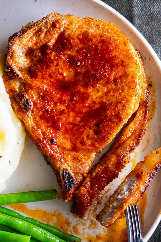 Pork Chops with mashed potatoes and green beans on a plate.