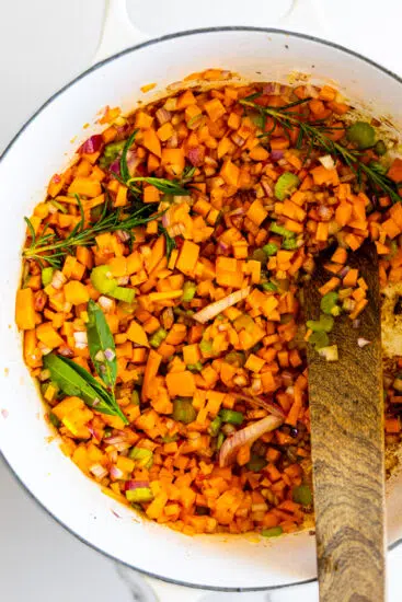 Mirepoix and herbs sautéing in large pot.