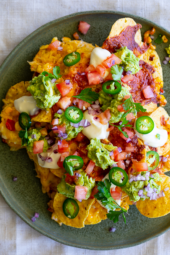 Air Fryer Nachos topped with guacamole, sour cream and diced tomatoes.