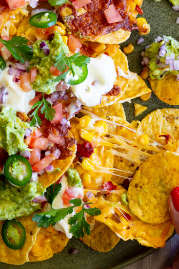Air Fryer Nachos with sour cream, guacamole and diced tomatoes.