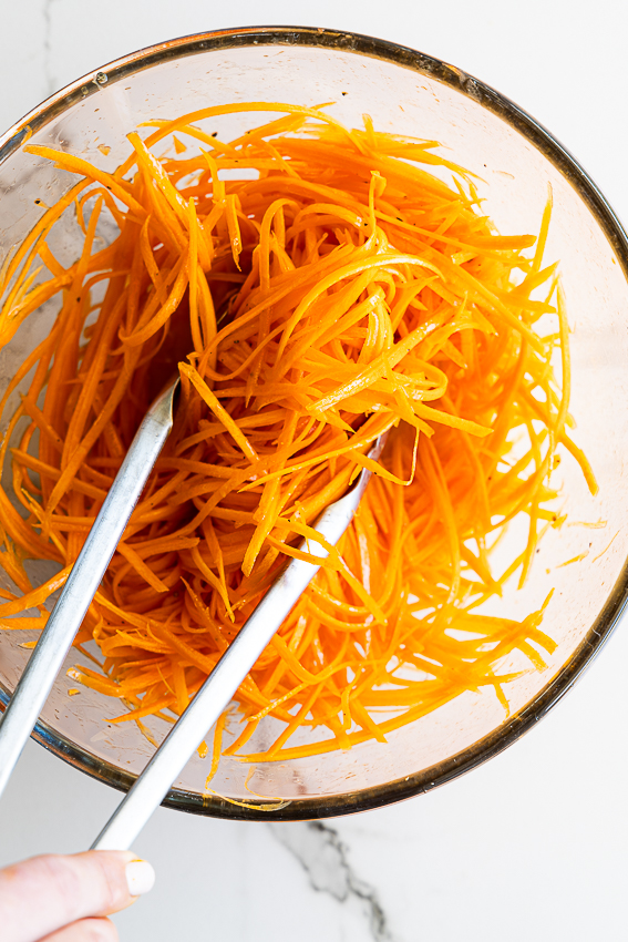 Carrot salad tossed with dressing.