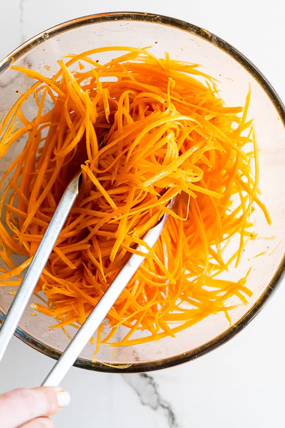 Carrot salad tossed with dressing.