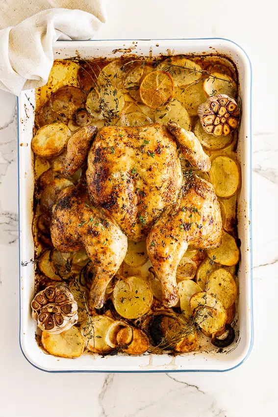 Oven Roasted Whole Chicken on potatoes, lemons and onions with fresh herbs.
