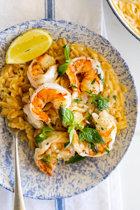 One pan shrimp and orzo in serving bowl with fresh herbs and lemon.