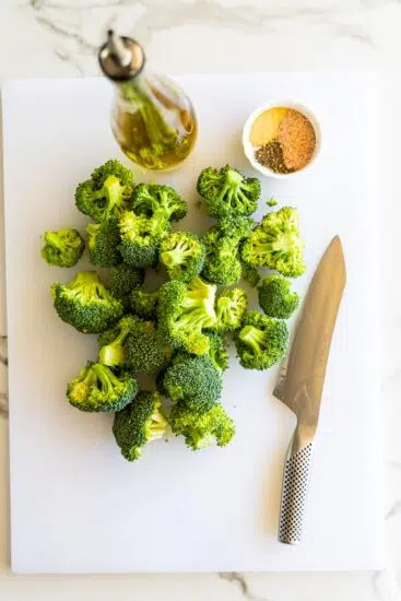 Broccoli, seasonings and olive oil on chopping board