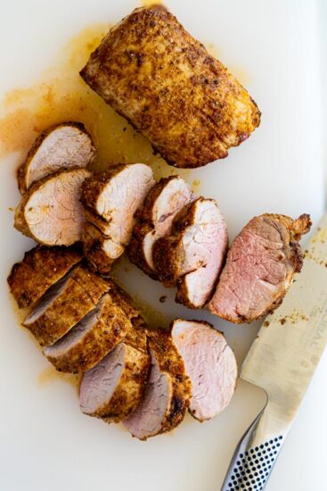 Air fryer pork tenderloin sliced on chopping board.