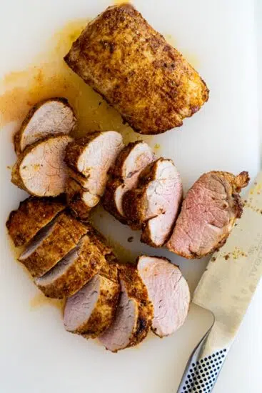 Air fryer pork tenderloin sliced on chopping board.