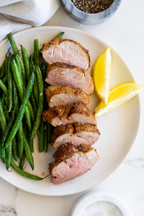 Air fryer pork tenderloin served with green beans.